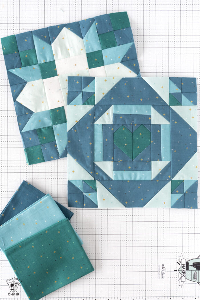 White blue and green quilt block on white cutting mat with folded fabrics