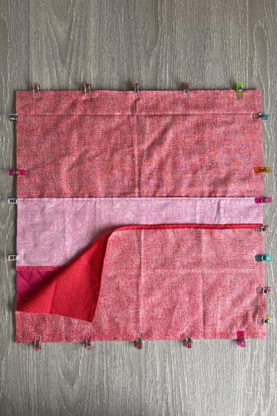 pink and red fabric on white table with pins