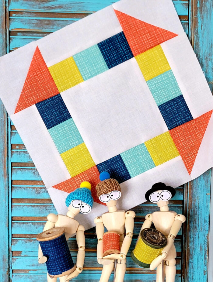 blue, yellow and orange quilt block hanging on a blue shutter