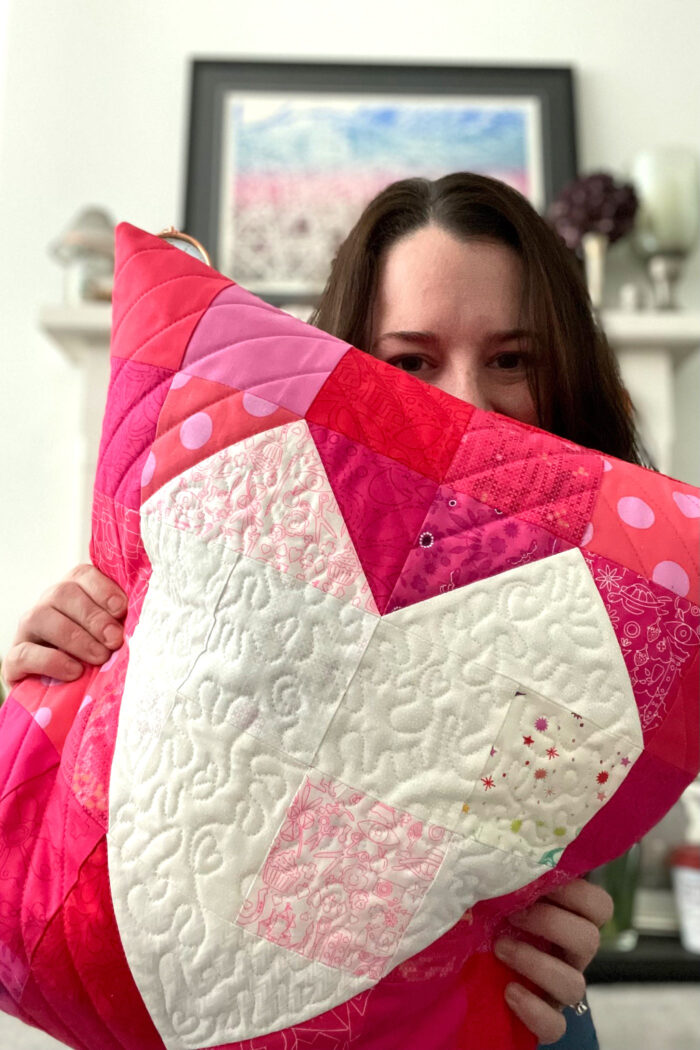 woman holding Quilted red pillow with white heart in the center