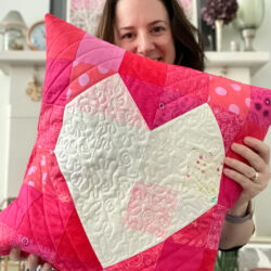 woman holding Quilted red pillow with white heart in the center