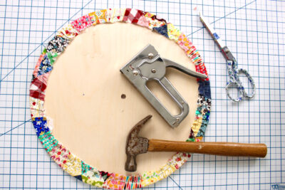 wood circle, patchwork fabric and staple gun on table