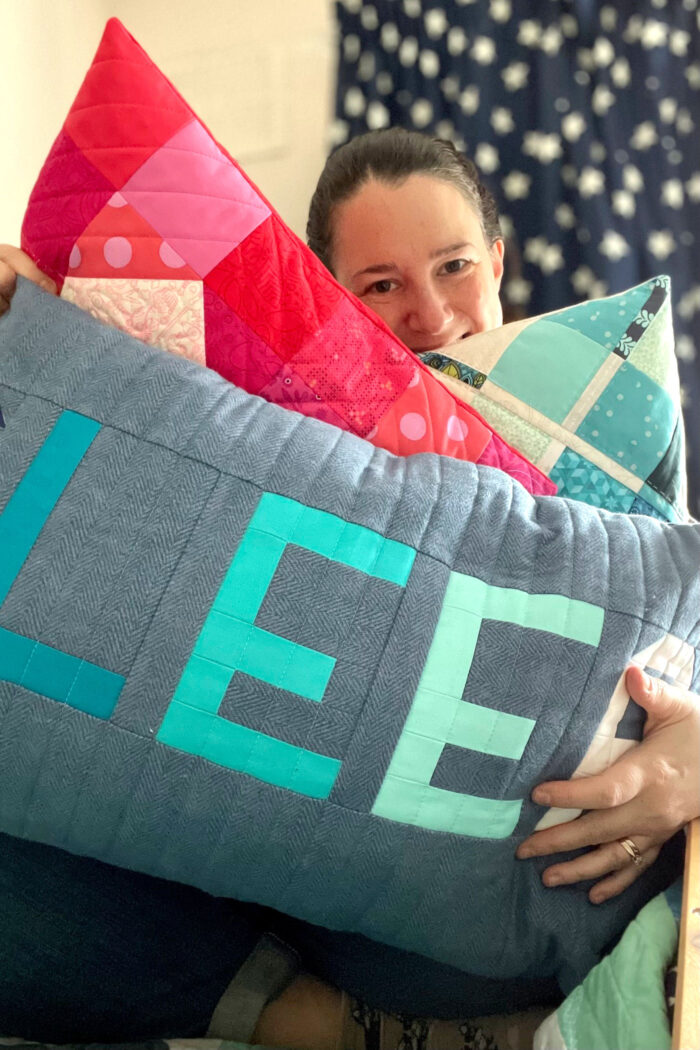 woman holding blue and green patchwork pillow