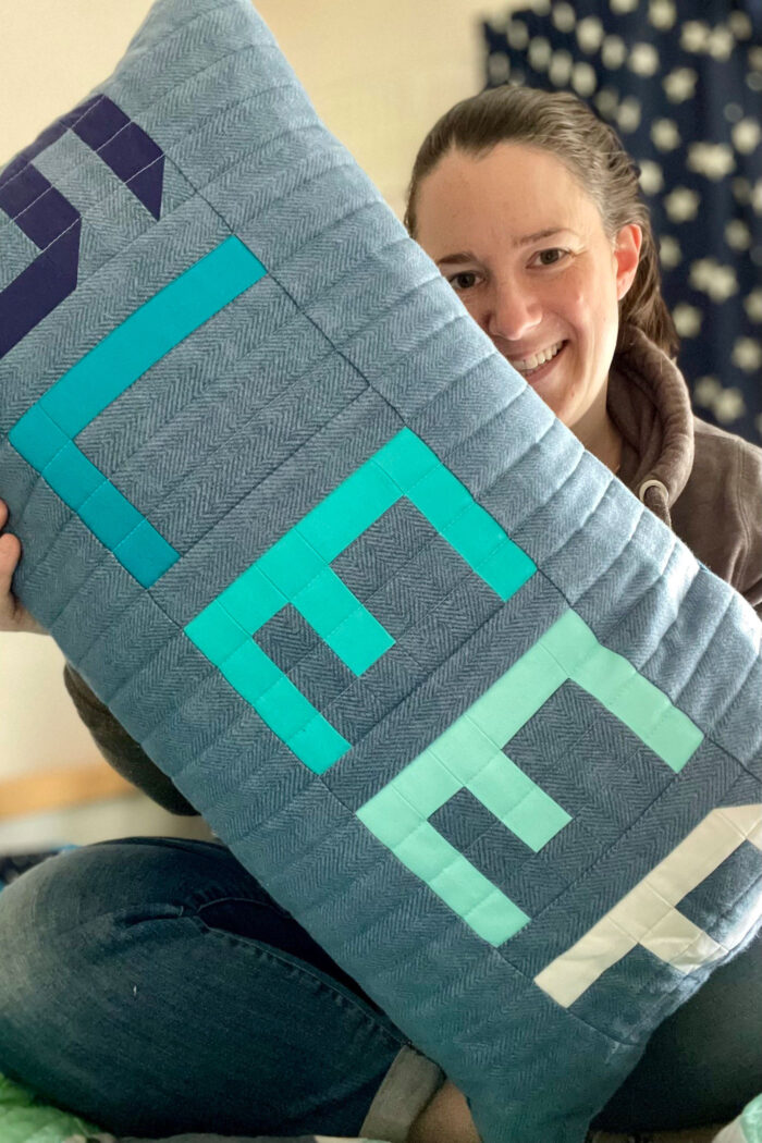 woman holding blue and green patchwork pillow