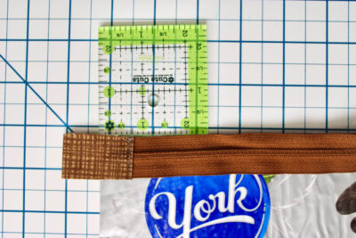 Quilt ruler, zipper and candy bar wrapper on cutting mat