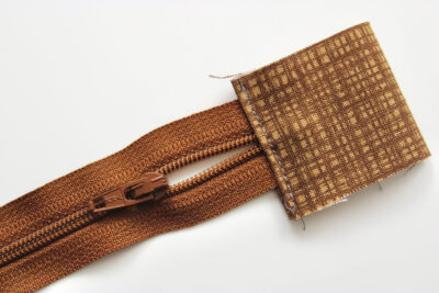 Brown rectangle of fabric covering end of zipper