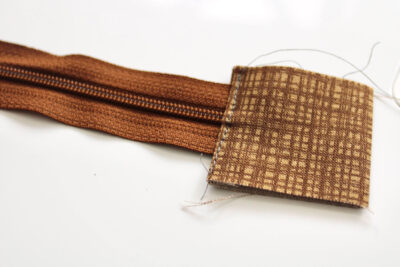 Brown rectangle of fabric covering end of zipper