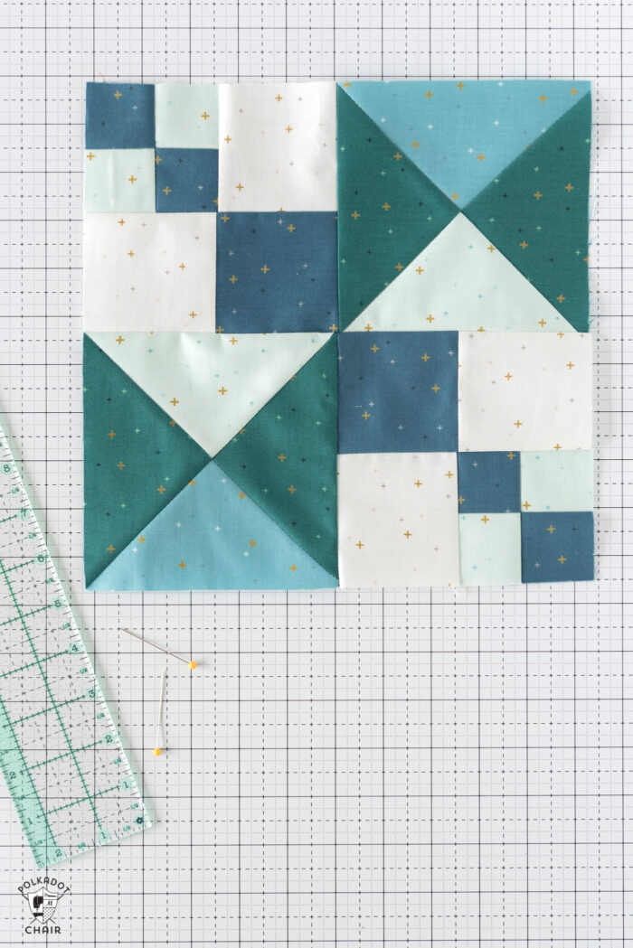 Blue and aqua quilt blocks on white cutting mat with quilting notions