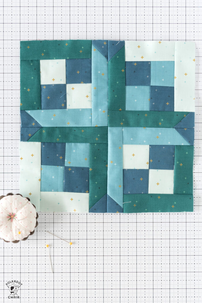 Blue and aqua quilt blocks on white cutting mat with quilting notions