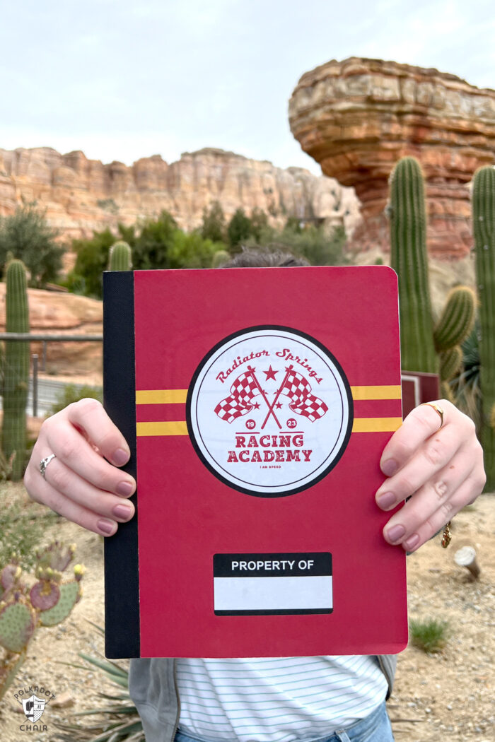 girl holding red and yellow notebook in front of canyon at Disneyland