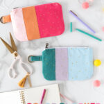Pink & orange and blue and green zippered bags on white table top with desk accessories