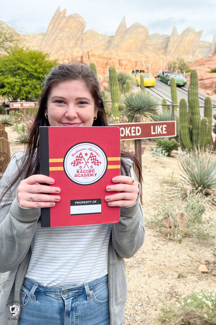 girl holding red and yellow notebook in front of canyon at Disneyland