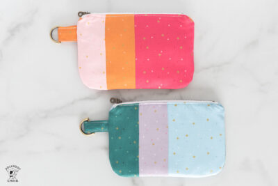 Pink & orange and blue and green zippered bags on white table top with desk accessories