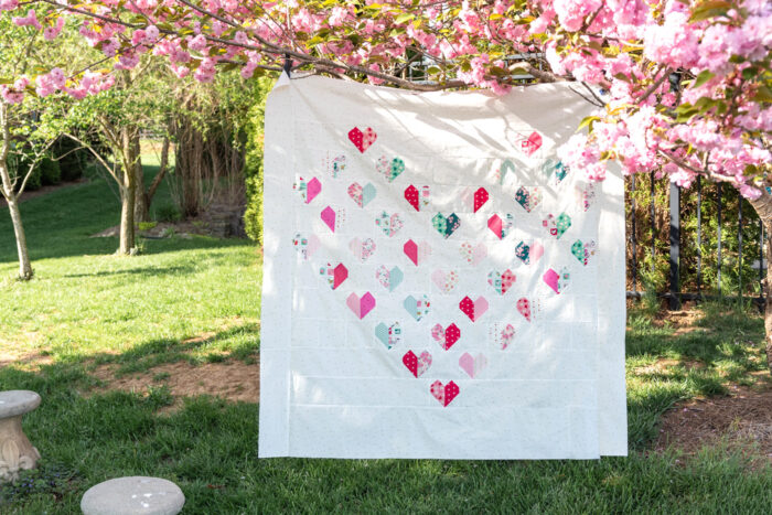 white quilt with hearts hanging on flowering tree outdoors