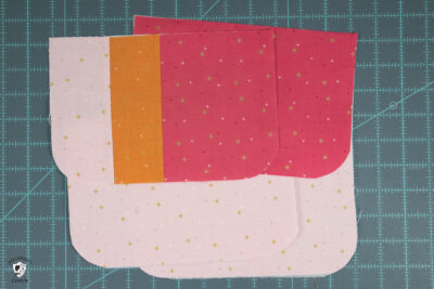 cut pieces of pink and orange fabric on cutting mat