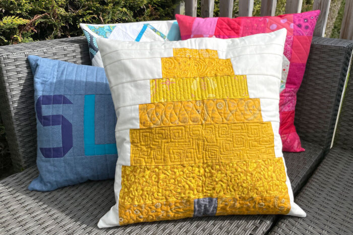 beehive pillow on wicker bench outdoors with other colorful pillows