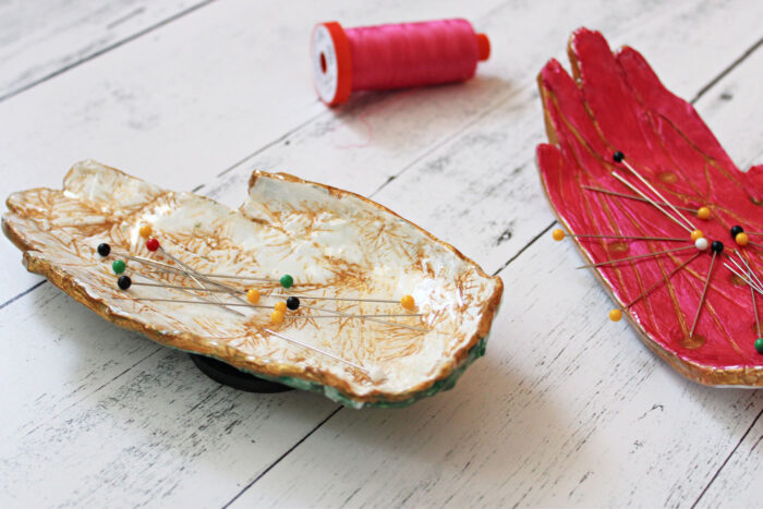 pink and ivory hand shaped pin dishes on white tabletop