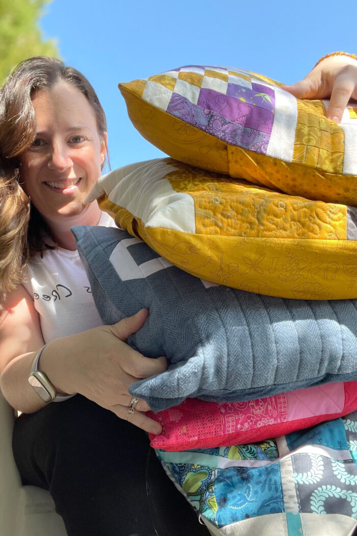 woman holding multiple colorful patchwork pillows