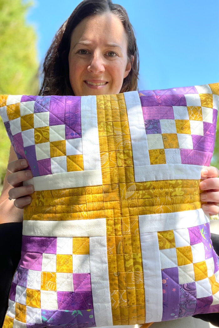 woman holding purple and gold union jack patchwork pillow