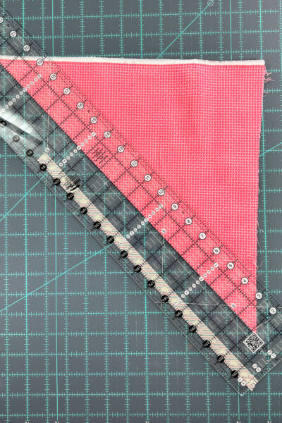 pink fabric being cut with quilt ruler
