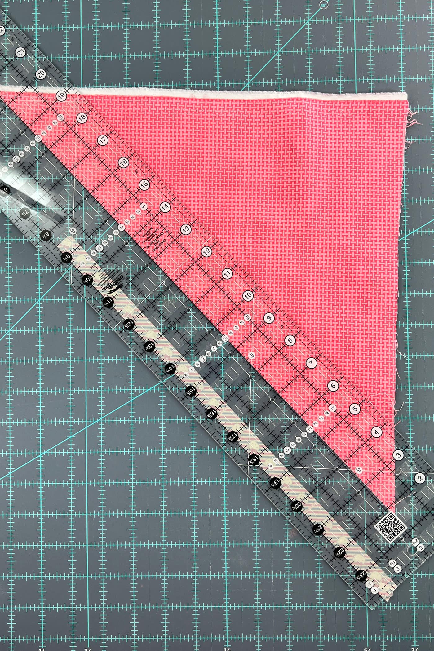 pink fabric being cut with quilt ruler