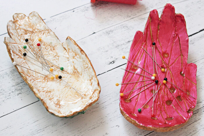 pink and ivory hand shaped pin dishes on white tabletop