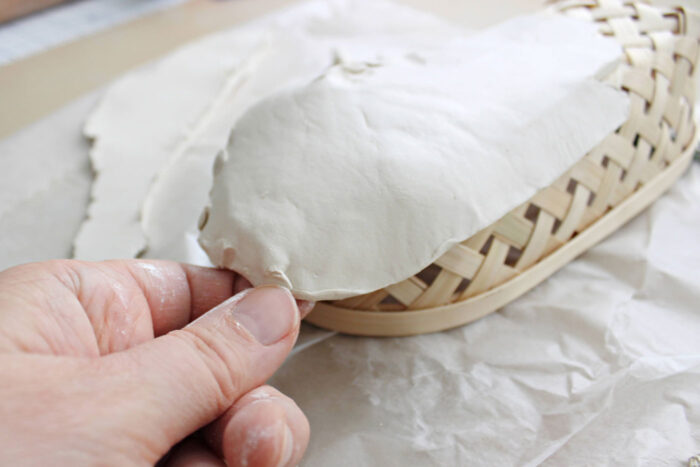 hand molding clay over basket