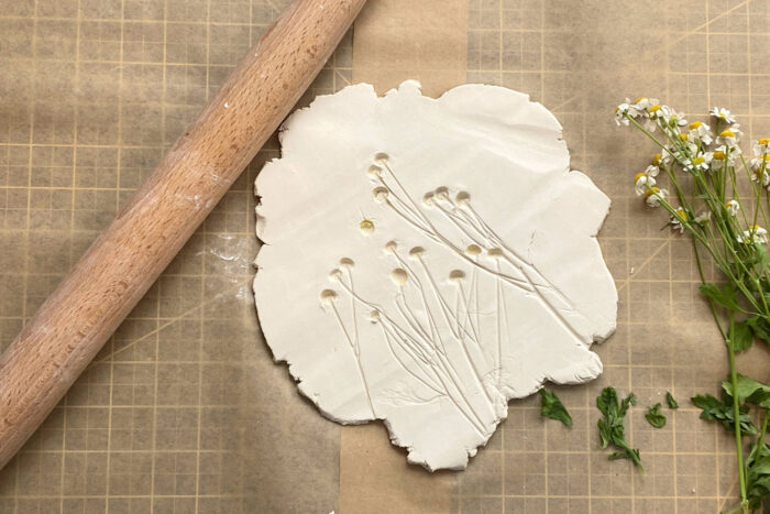 imprint of flowers rolled into air dry clay on brown paper