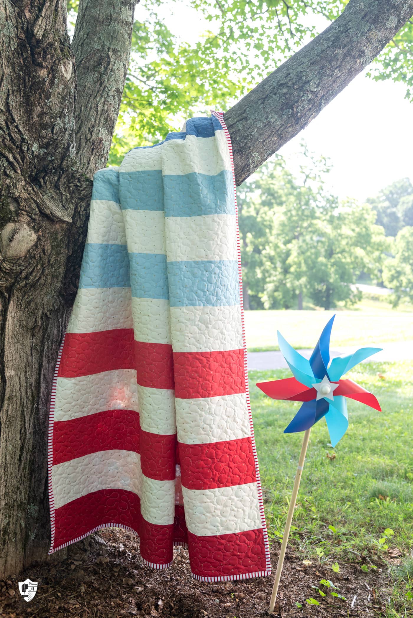 striped quilt hanging on tree outdoors with pinwheel