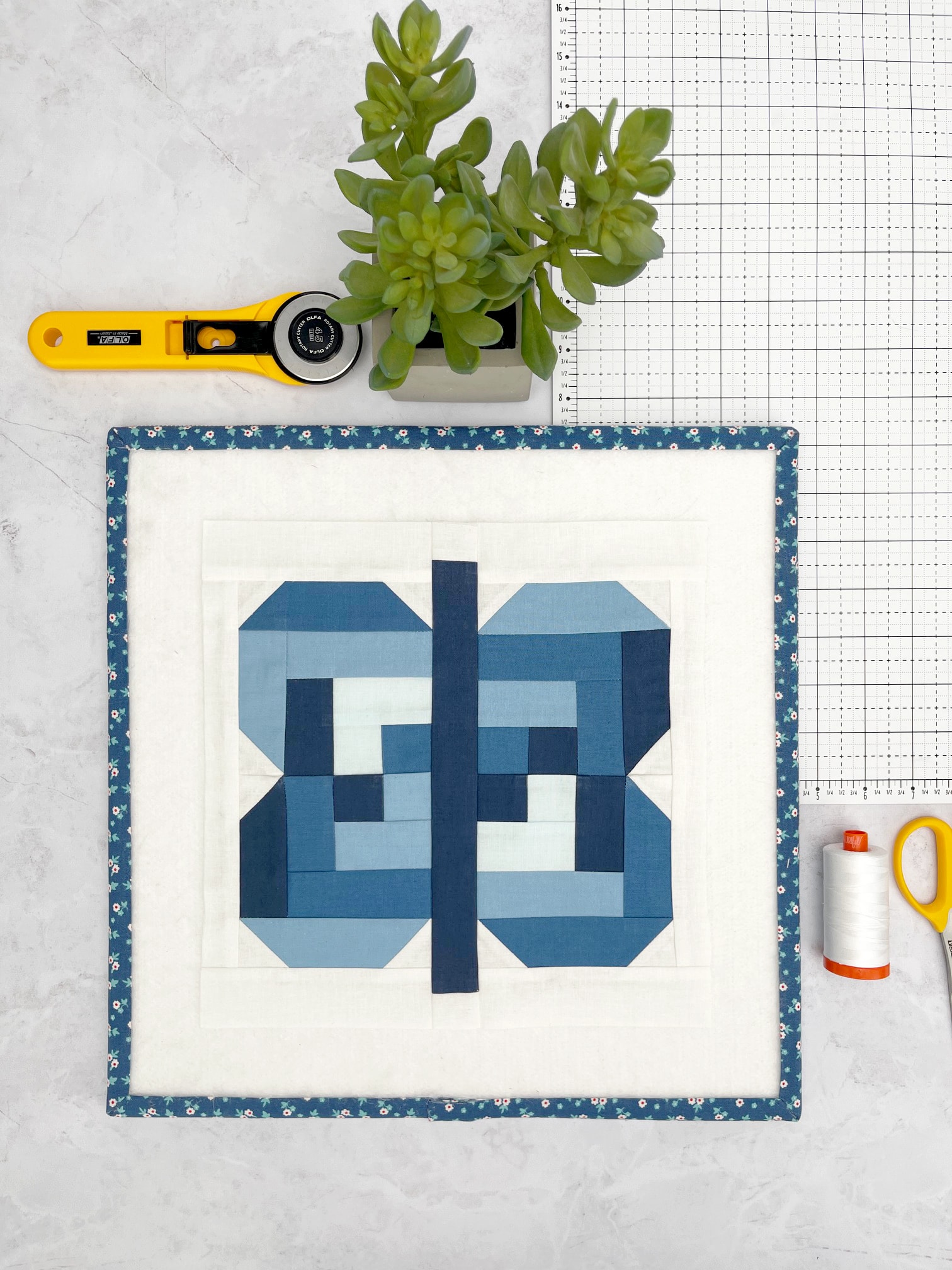 blue and white quilt block on white table with quilt notions