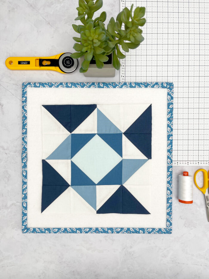 blue and white quilt block on white table with quilt notions