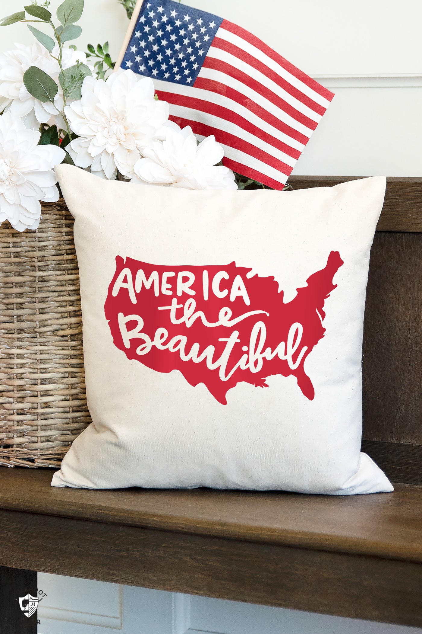 Patriotic pillow on wood bench with american flags and flowers