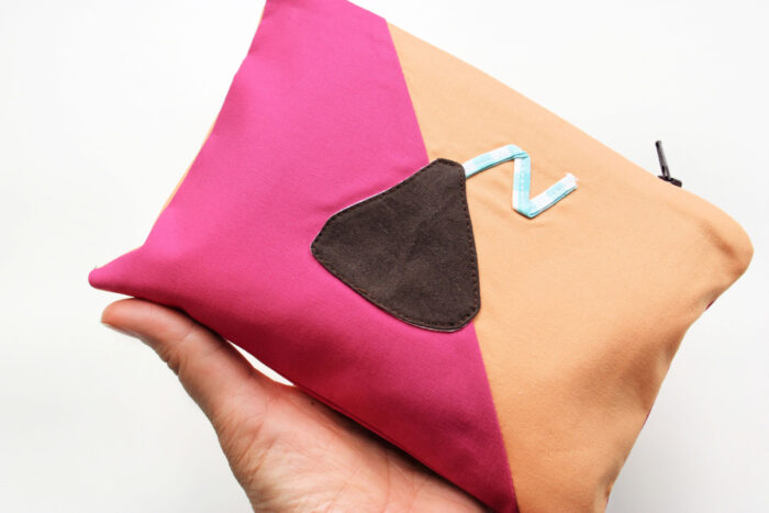 hand holding Pink and peach zip pouch with chocolate kiss applique on white table