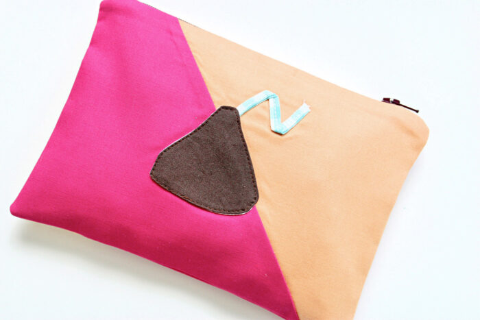 Pink and peach zip pouch with chocolate kiss applique on white table