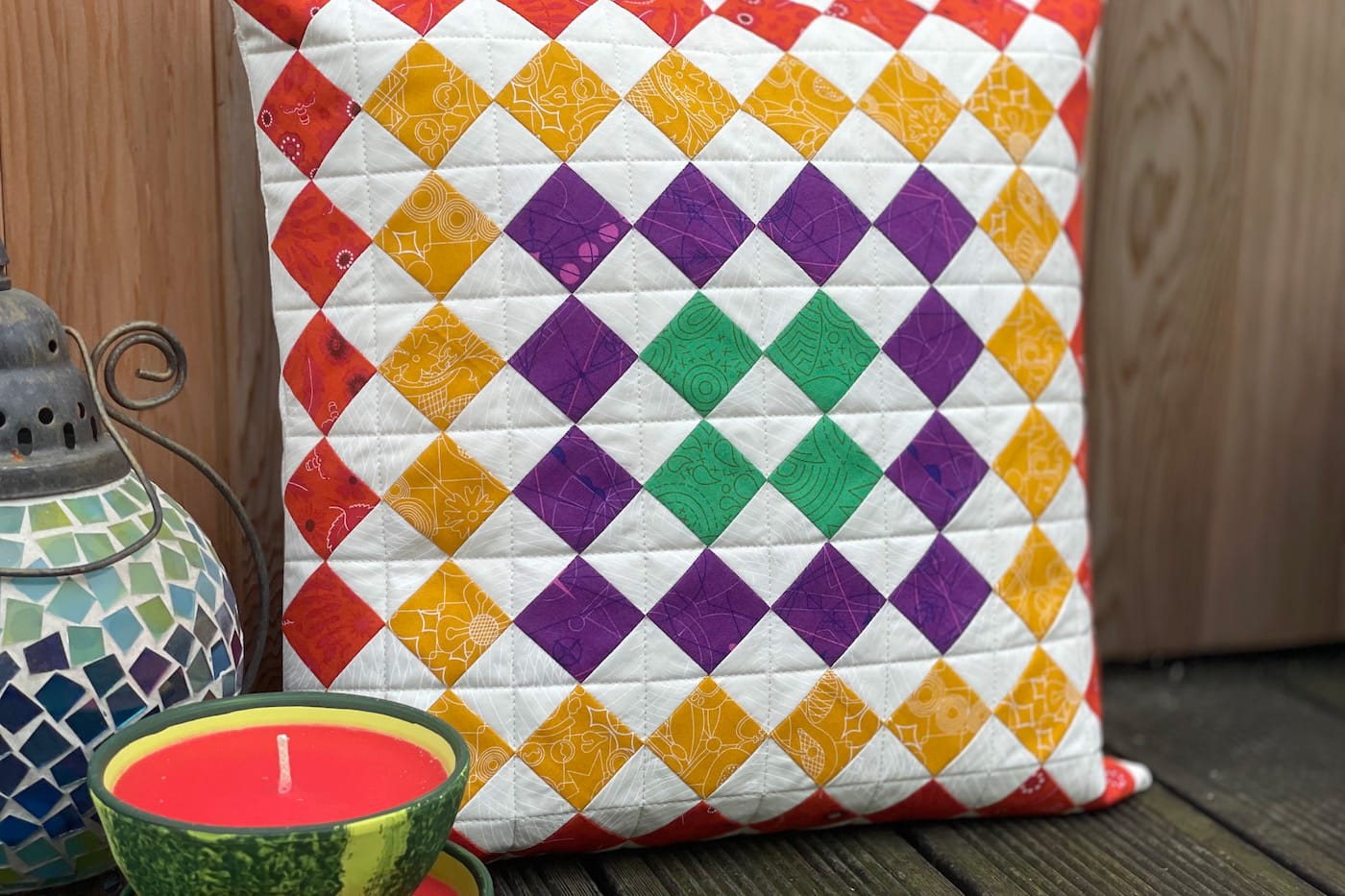 colorful pillow on outdoor deck with candle