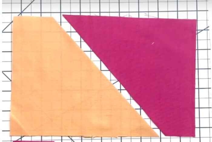 two triangles of colorful fabric on white cutting mat
