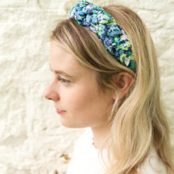 girl wearing blue braided headband in front of brick wall