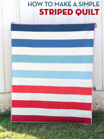 red white and blue striped quilt in front of white barn