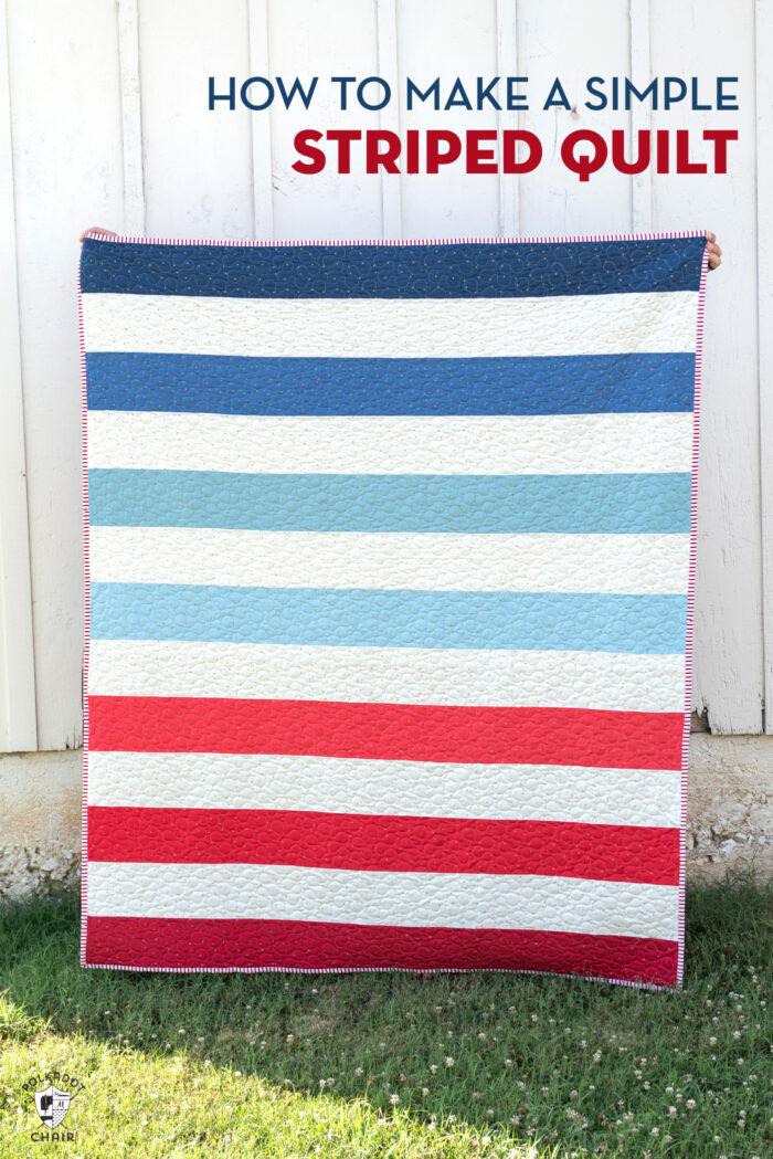 red white and blue striped quilt in front of white barn