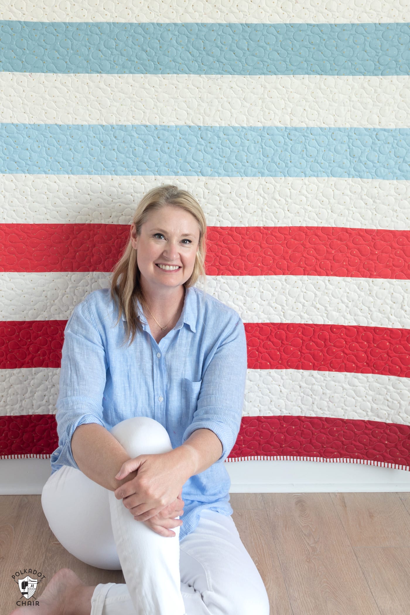 woman in blue shirt sitting in front of red white and blue quilt