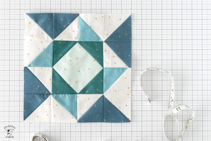 aqua, blue and green quilt block on white cutting mat with notions