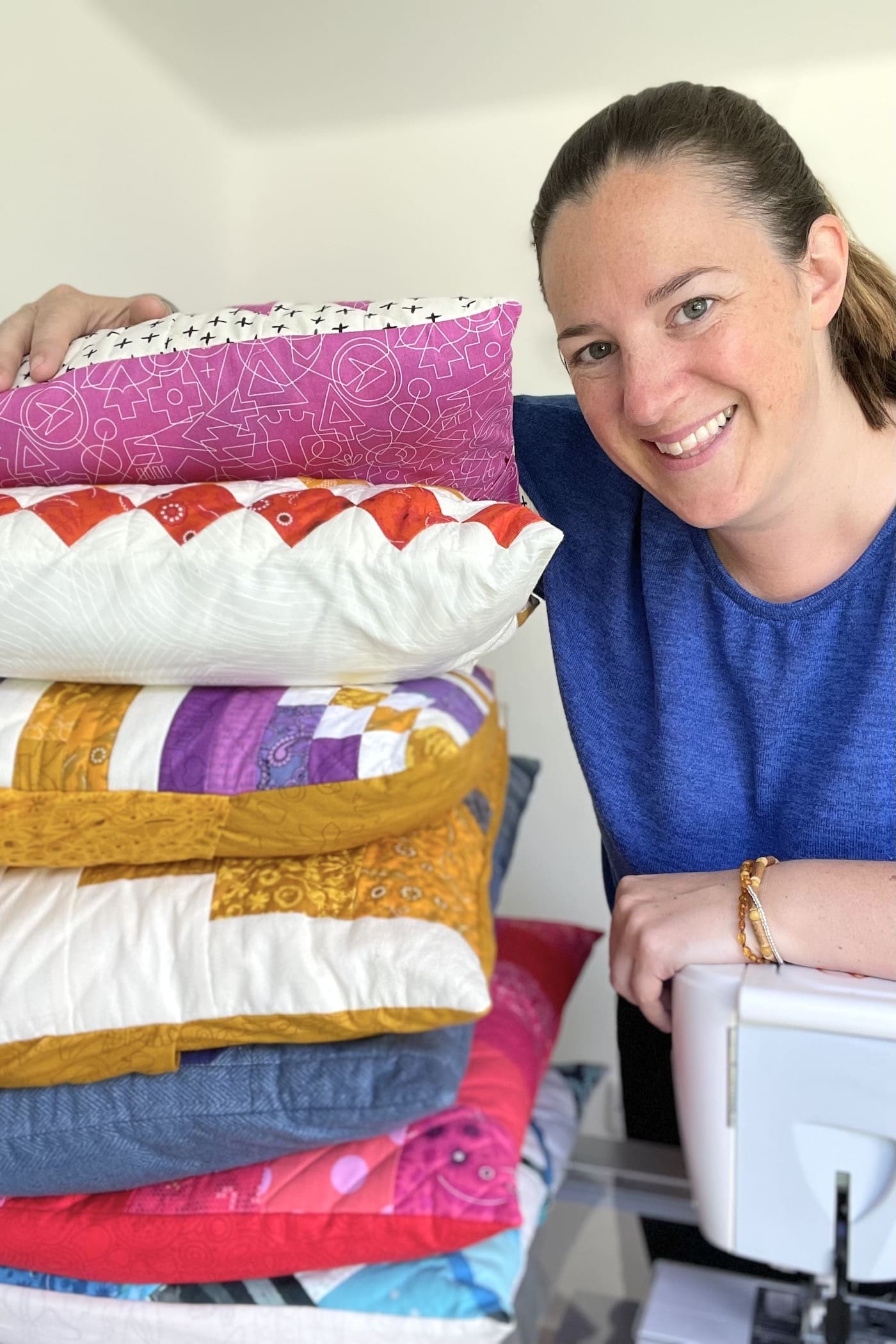 woman next to stack of quilted pillows