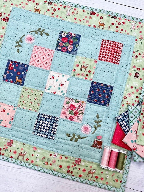 Colorful blue and green mini quilt with fabric and notions
