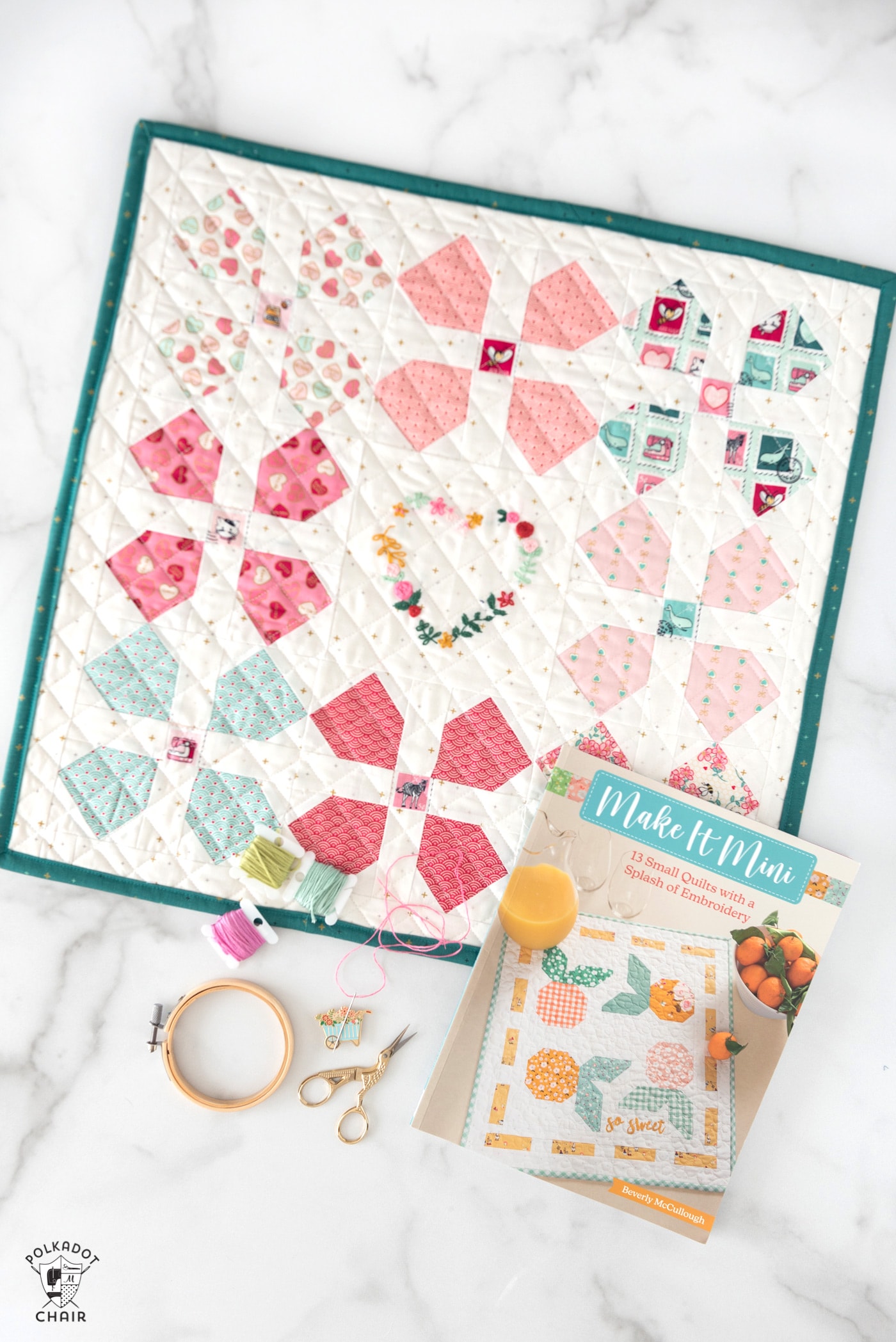 Mini quilt, book and sewing notions on white tabletop