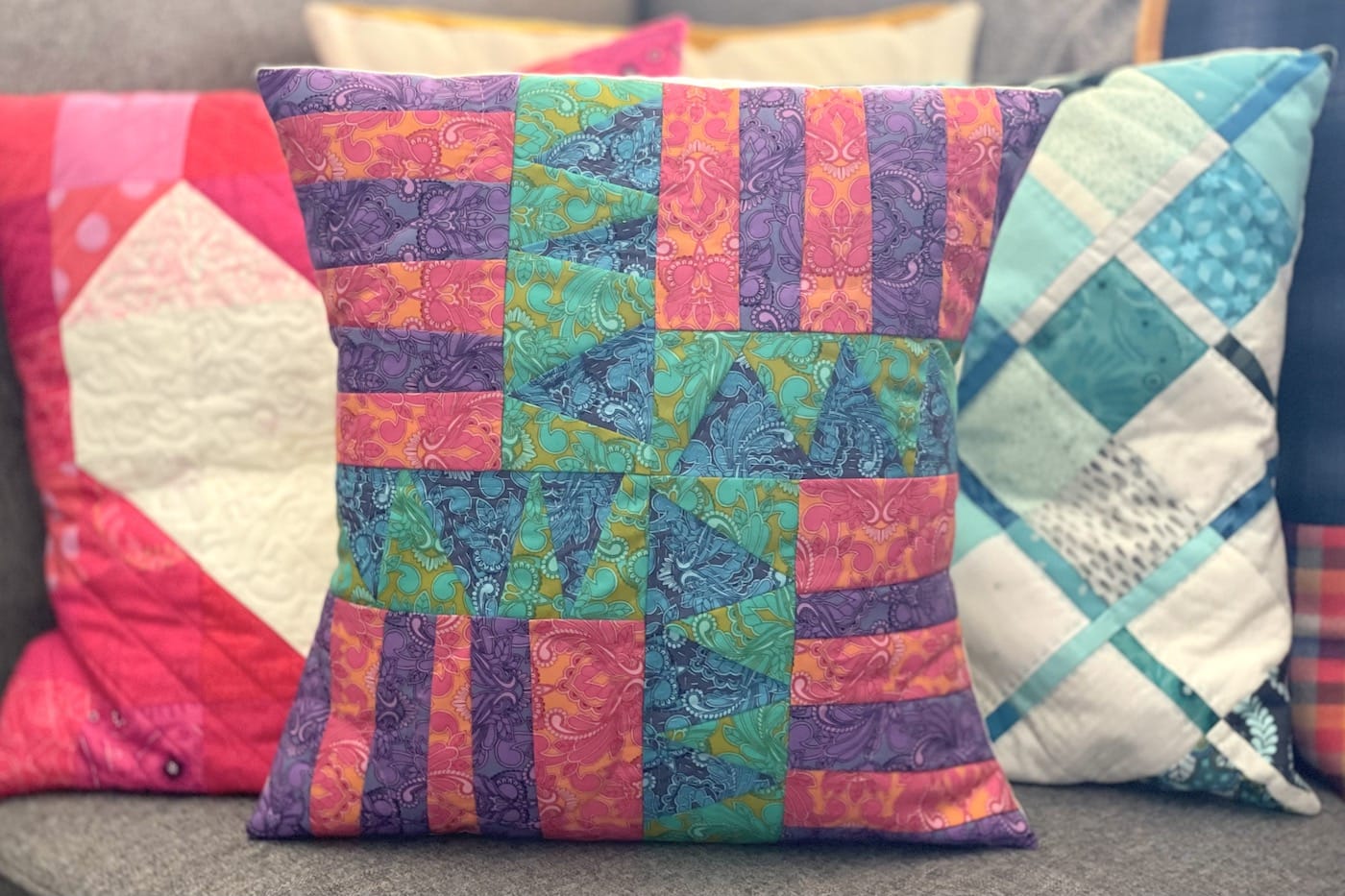 Blue, green, purple and red patchwork pillow on couch