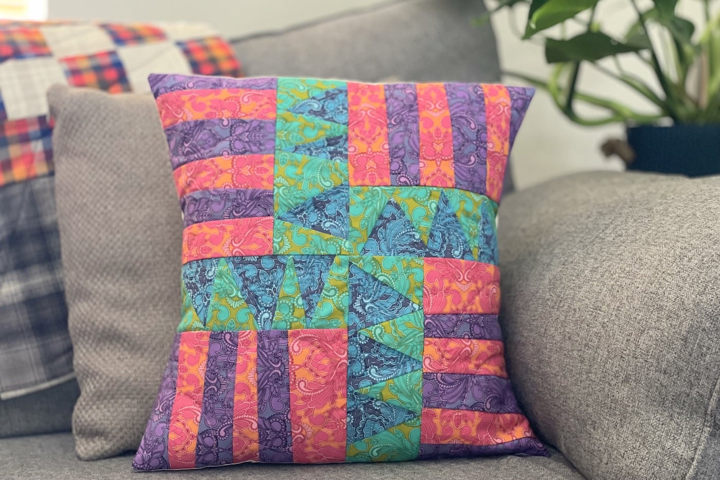 Blue, green, purple and red patchwork pillow on couch