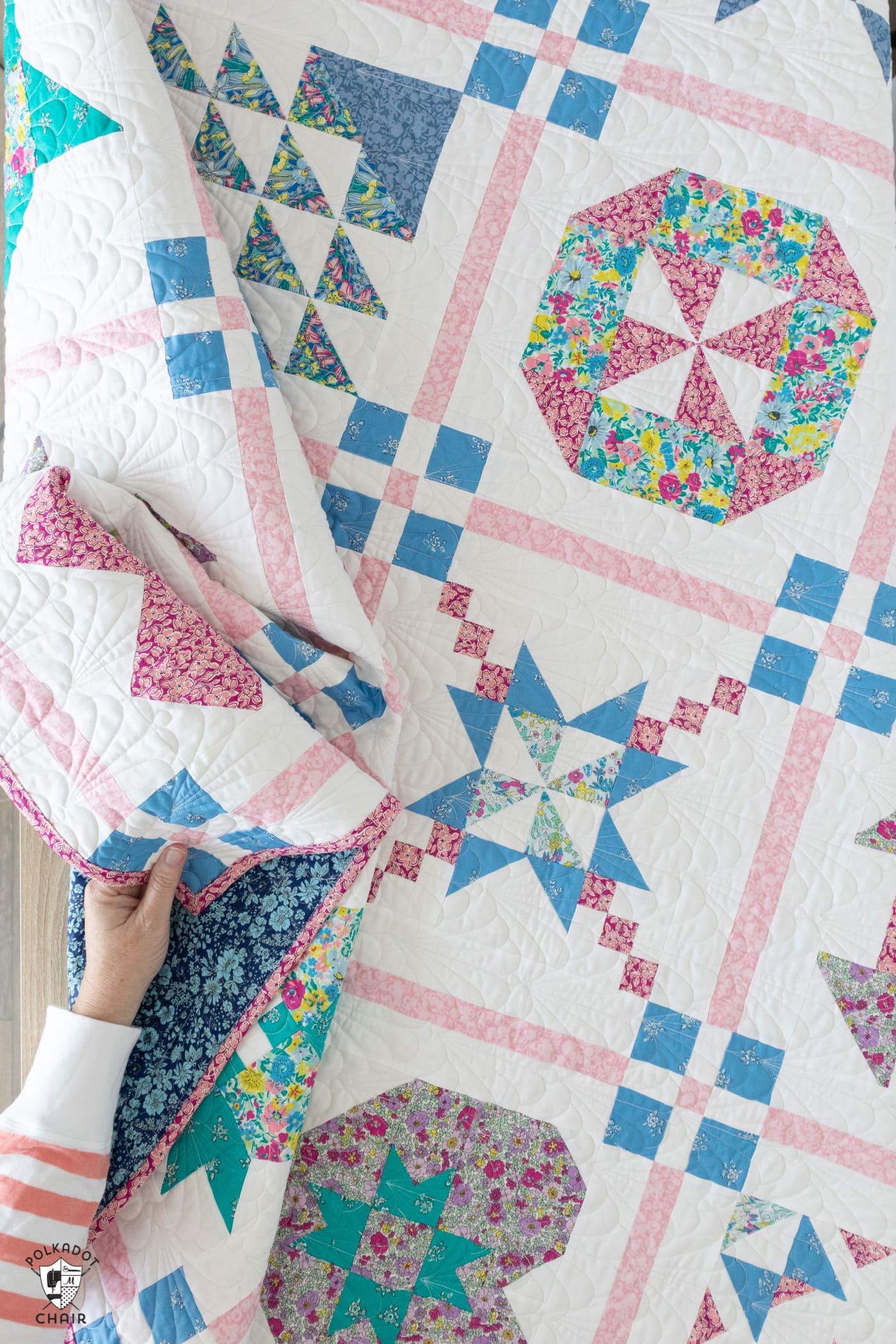 hand holding finished blue, pink and white quilt