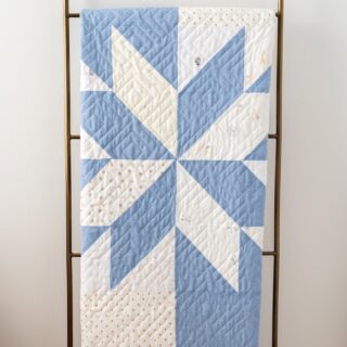 blue and white star baby quilt on quilt rack in white room