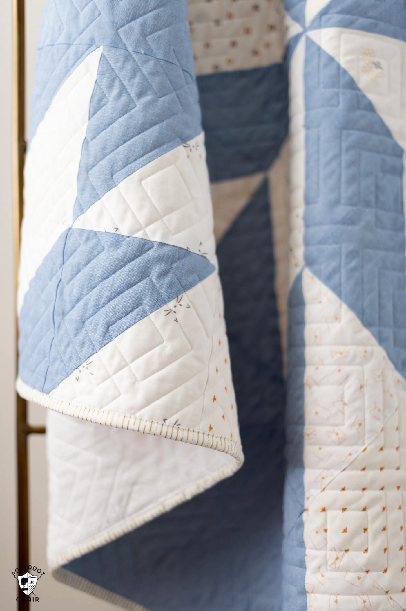 blue and white star baby quilt on quilt rack in white room