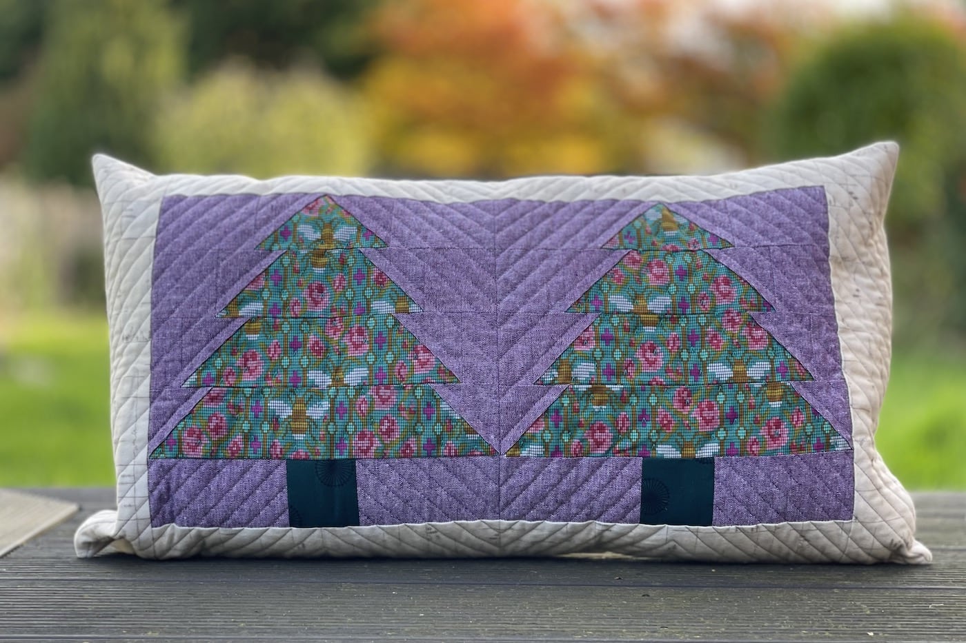 Purple and green pillow with patchwork pieced evergreen trees outdoors